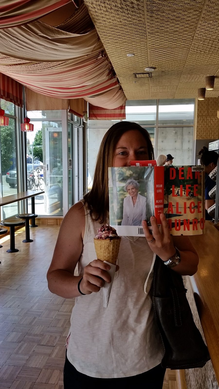 Hiding behind a copy of Alice Munro’s Dear Life while holding an ice cream cone