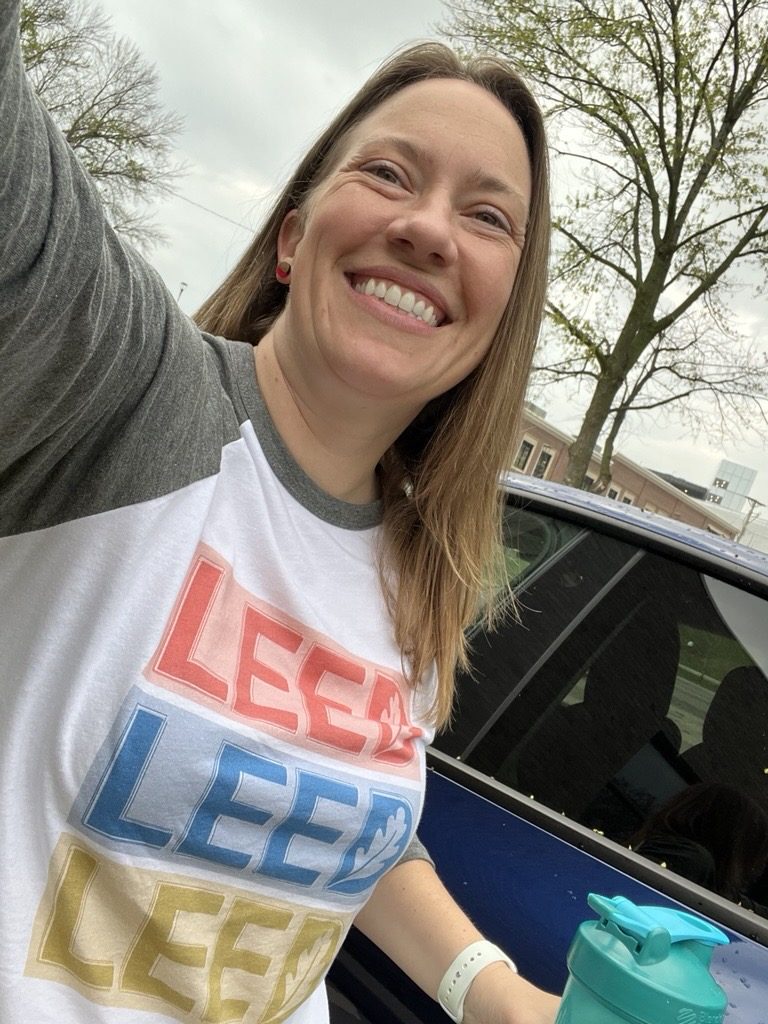 Smiling selfie in a raglan T-shirt printed with LEED three times in coral, blue, and gold
